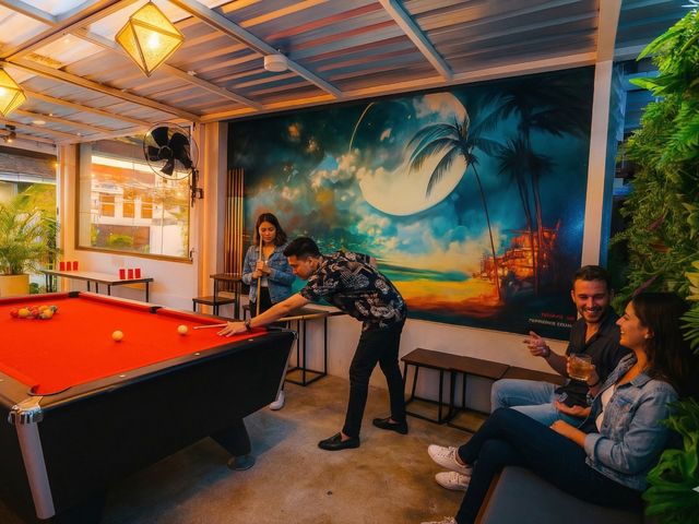 Travelers playing pool at Eclipse with tropical moon mural